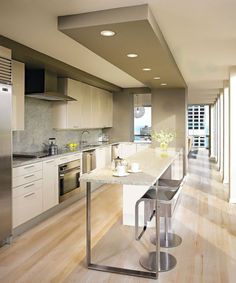 a modern kitchen with stainless steel appliances and white counter tops, along with hardwood flooring