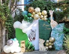 a jungle themed birthday party with balloons, animals, and other decorations on the ground