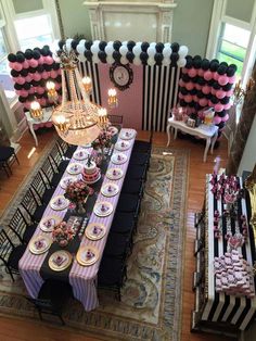 a table set up for a party with black, white and pink decorations