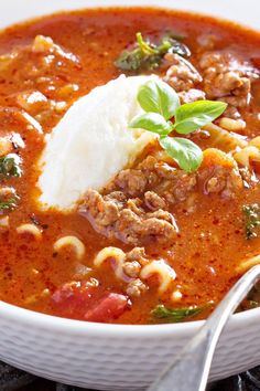 a white bowl filled with pasta and meat soup on top of a black tablecloth