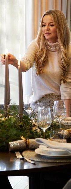 a woman sitting at a table with candles in front of her