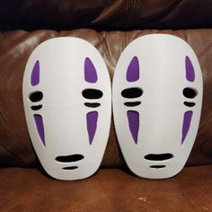 two white and purple masks sitting on top of a brown couch