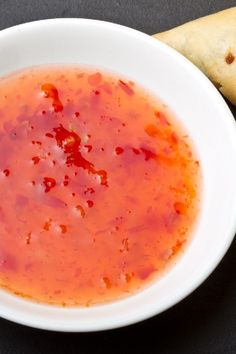 a bowl of tomato sauce next to some pita bread on a black counter top