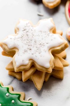 several decorated cookies sitting on top of a white table next to christmas trees and snowflakes