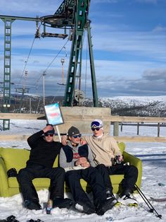 three men sitting on a green couch in the snow