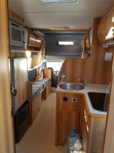 the inside of an rv with wood paneling and stainless steel appliances