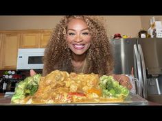 a woman with curly hair standing in front of a plate of food on a kitchen counter