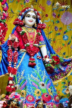 an idol is displayed in front of a colorful wall with flowers and garlands on it