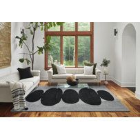 a living room filled with furniture and a large window covered in plants on top of a hard wood floor