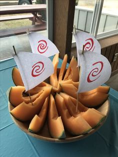 there is a boat made out of melon and cheese on the table with flags