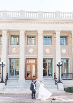 a bride and groom standing in front of a large building with columns on each side