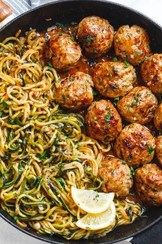 spaghetti and meatballs in a skillet with lemon wedges on the side, ready to be eaten