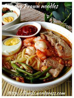 a bowl filled with noodles, meat and vegetables next to an egg on top of a table