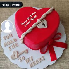 a red heart shaped cake with a name and photo on the top, sitting on a table