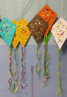 four kites are hanging on the wall with streamers in front of them and one has a face