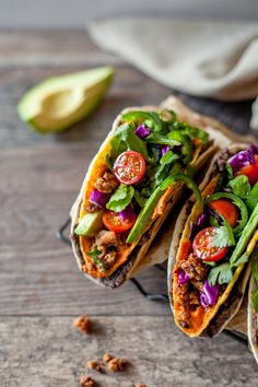 two tacos filled with meat and veggies on top of a wooden table