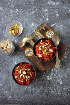 two bowls filled with food sitting on top of a wooden tray next to spoons