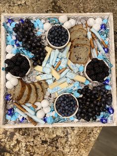 a tray filled with crackers, blueberries and blackberries on top of a granite counter