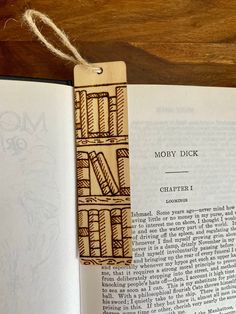 an open book with a wooden bookmark attached to it