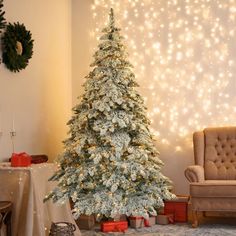 a decorated christmas tree in a living room with lights on the wall and presents under it