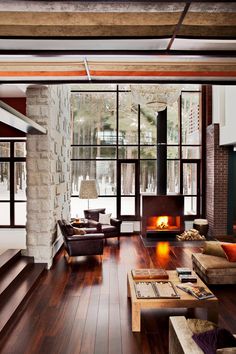 an open living room with wood floors and large windows, along with a fireplace in the center