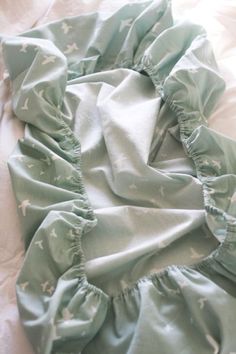 an unmade bed with blue sheets and white stars on it's ruffled edges