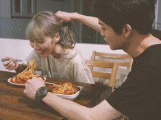 two people sitting at a table eating spaghetti