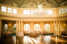 an empty ballroom with chandelier and tables