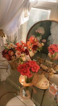 flowers in vases are sitting on a table next to a mirror and other items