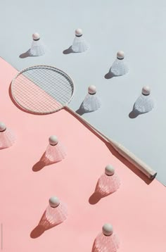 there are many small white objects on the pink surface and one is holding a tennis racket