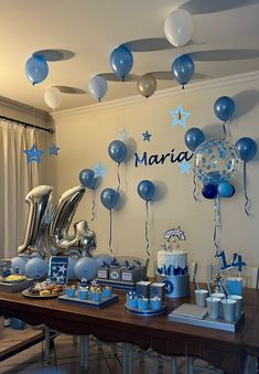 a table with blue and white balloons, silver foil stars, and other items on it