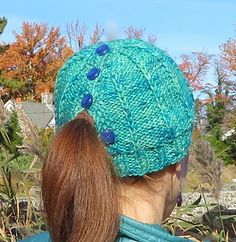 a woman wearing a green knitted hat with blue buttons on the back of her head