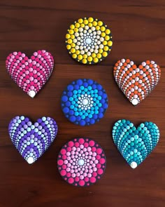 six heart shaped magnets are arranged on a wooden surface with different colors and shapes