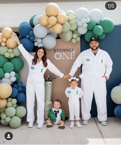 a man and woman holding hands while standing next to two children in front of balloons