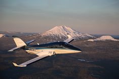 an airplane flying over the mountains with snow on them and a mountain in the background