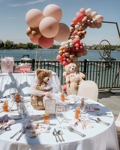 a teddy bear sitting at a table with balloons