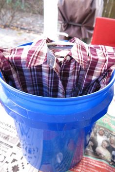 there is a blue bucket with some cloth in it on the table next to a newspaper