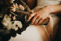 a woman in white dress holding a bouquet of flowers with her hands on the bride's lap