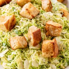 a salad with croutons and lettuce in it on a white plate