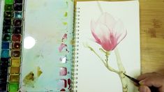 someone is painting a flower with watercolors on paper