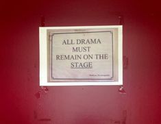 a sign that is on the side of a red wall saying, all drama must remain on the stage