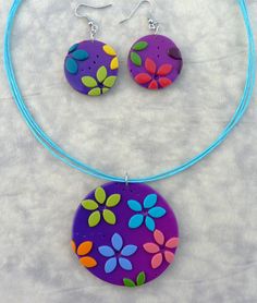 a necklace and earring set with flowers painted on the front, blue cord attached to it