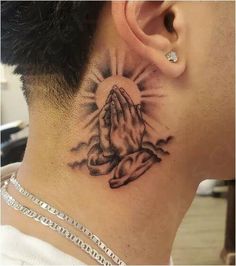 a close up of a person's neck with a praying hand tattoo on it