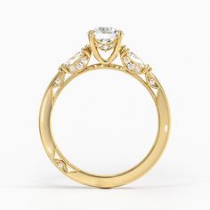 a yellow gold engagement ring with three stones on the side and an intricate design around the band