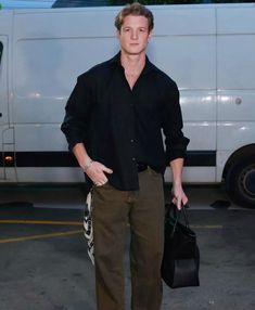 a man in black shirt and khaki pants standing next to a white van