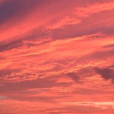 a person flying a kite in the sky at sunset or sunrise with pink and orange clouds