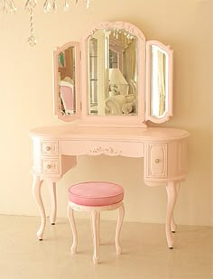 a pink dressing table with a stool and mirror