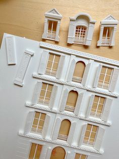 the model house is made out of white paper and has windows on each side with shutters