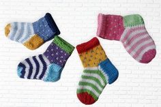 four pairs of colorful socks hanging on a brick wall next to a white brick wall