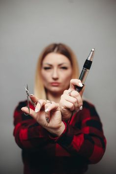 a woman holding scissors in her hands and looking at the camera